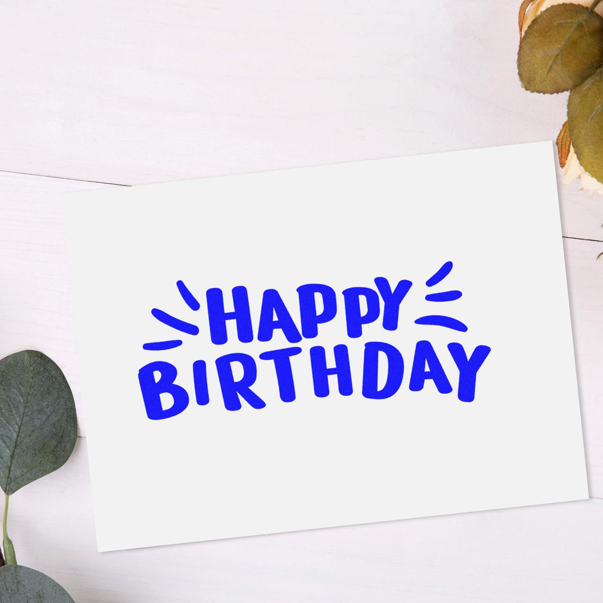 Blue HAPPY BIRTHDAY stamp on white card with eucalyptus leaves, showcasing stamp and seal products.