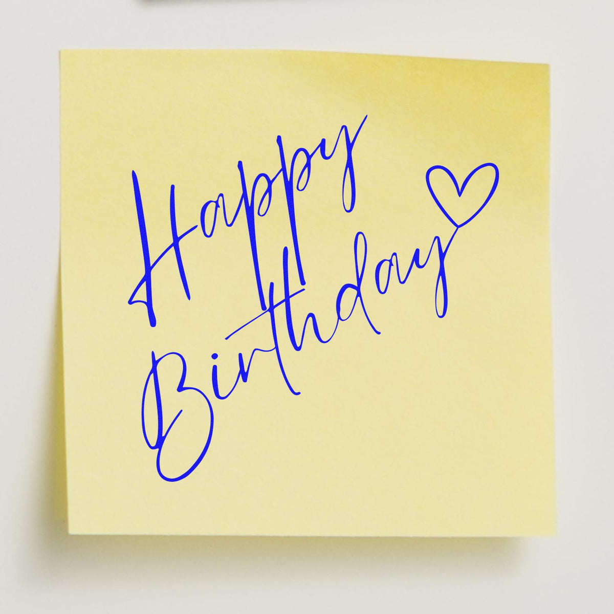 Birthday stamp and seal design with blue cursive Happy Birthday and heart on a pale yellow note.