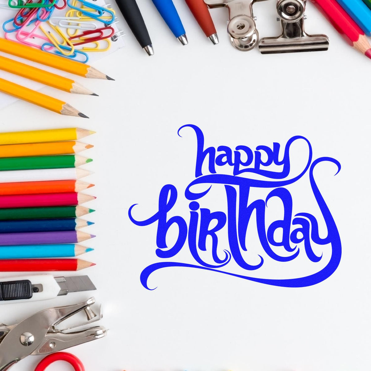 Blue Happy Birthday stamp and seal with colorful pencils, paper clips, and metal clips on white background.