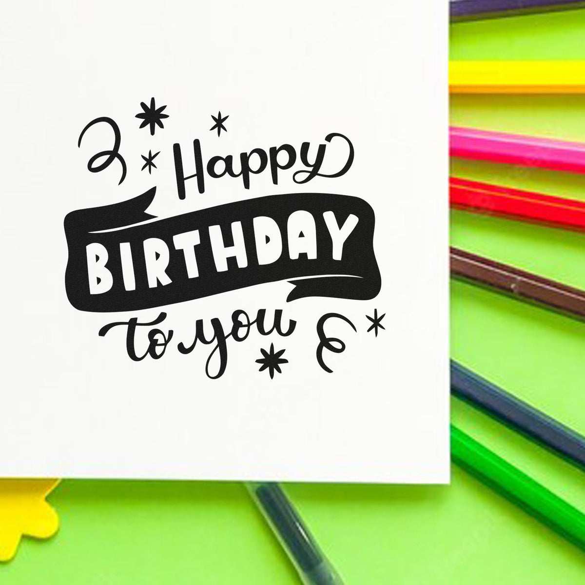 Black Happy Birthday to You stamp on white card, surrounded by neon green, pink and yellow stamp and seal products.