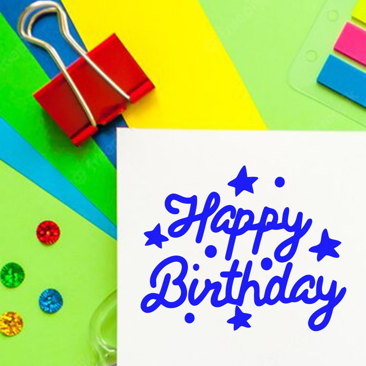 Colorful stamp and seal set with blue Happy Birthday text, stars, and paper clips on bright green, yellow, and blue backgrounds.