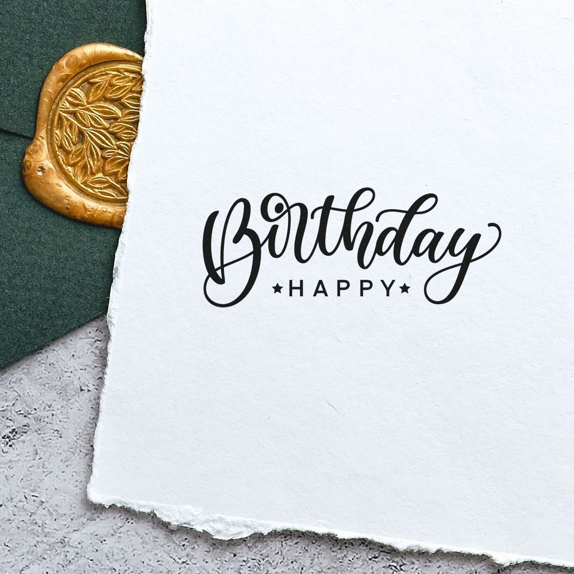 Black Birthday Happy stamp on white handmade paper, with a partial gold wax seal on dark green background.