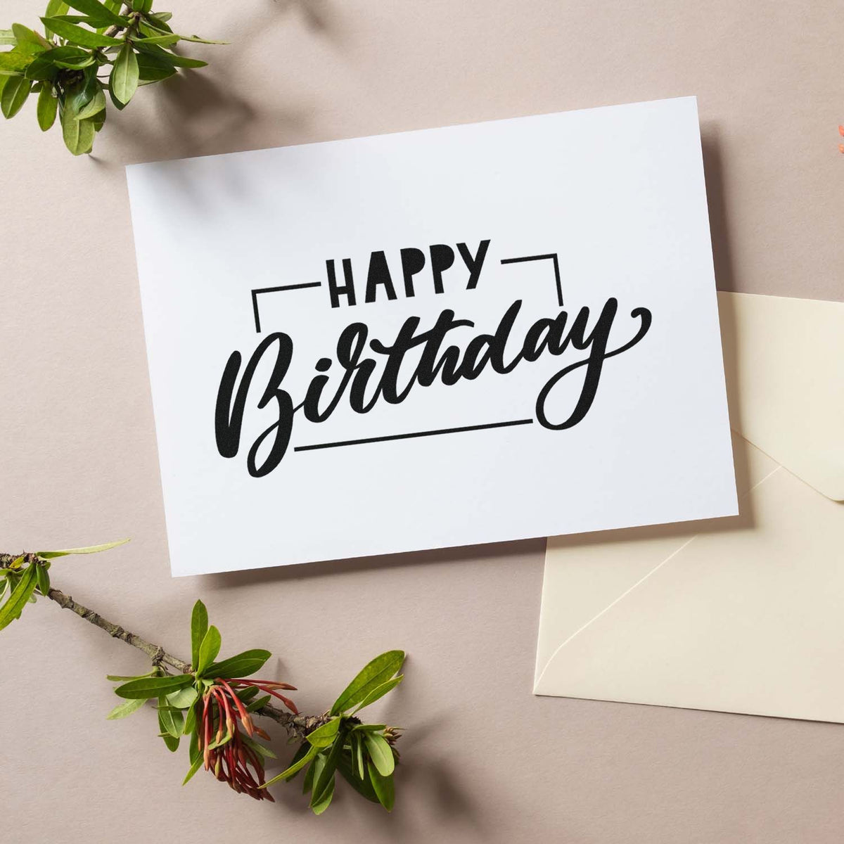 Black Happy Birthday stamp on white card with cream envelope and green leaves, styled for stamp and seal products.