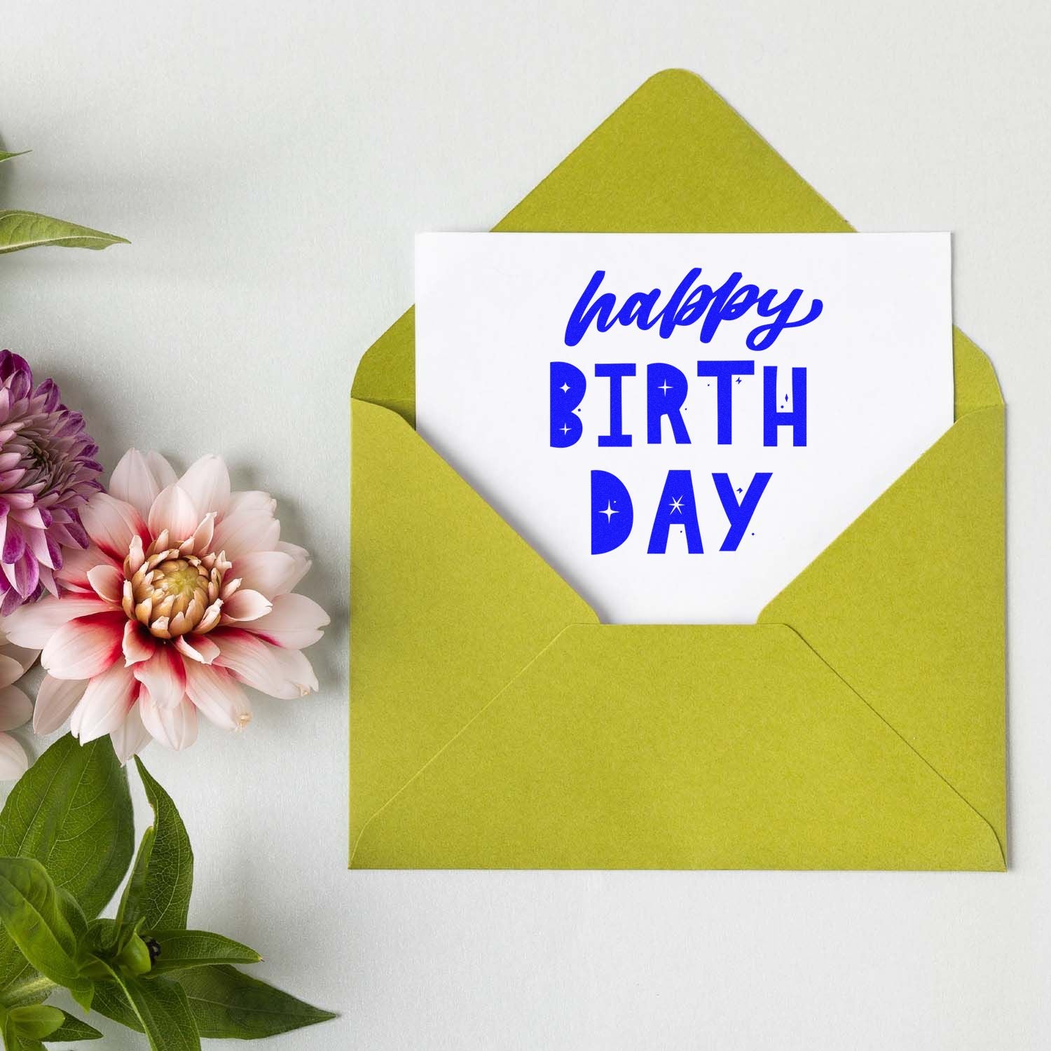 Happy Birthday stamp and seal design in blue on white card in lime green envelope, with pink and purple flowers