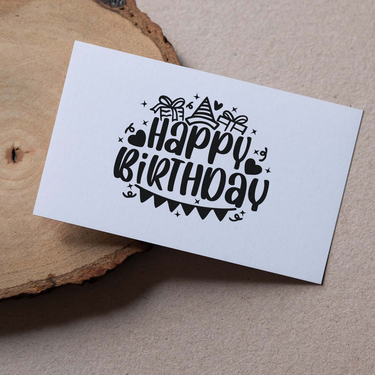 Black Happy Birthday stamp seal on white card, with party hat, gifts, hearts and stars on a tan rustic background.