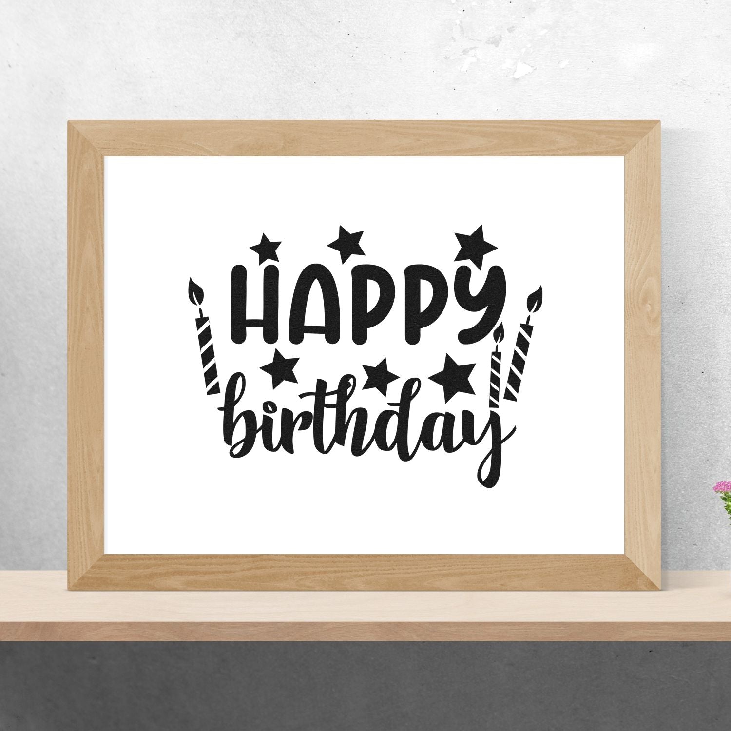 Black Happy Birthday stamp design with stars and candles in a light wood frame.
