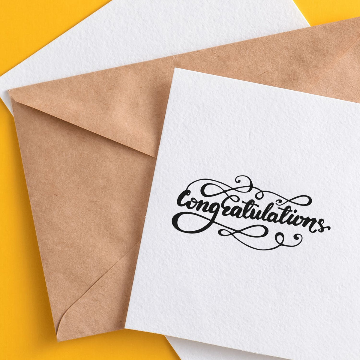 White card with black Congratulations stamp over kraft envelope on a bright yellow background, showcasing stamp and seal products.