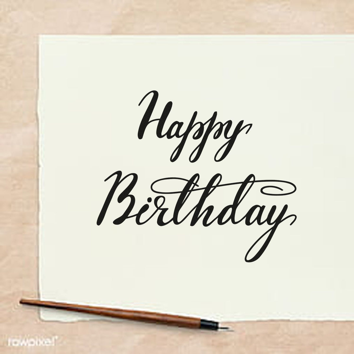 Black Happy Birthday stamp and seal design on white paper, with elegant script and flourish beside a brown pen.