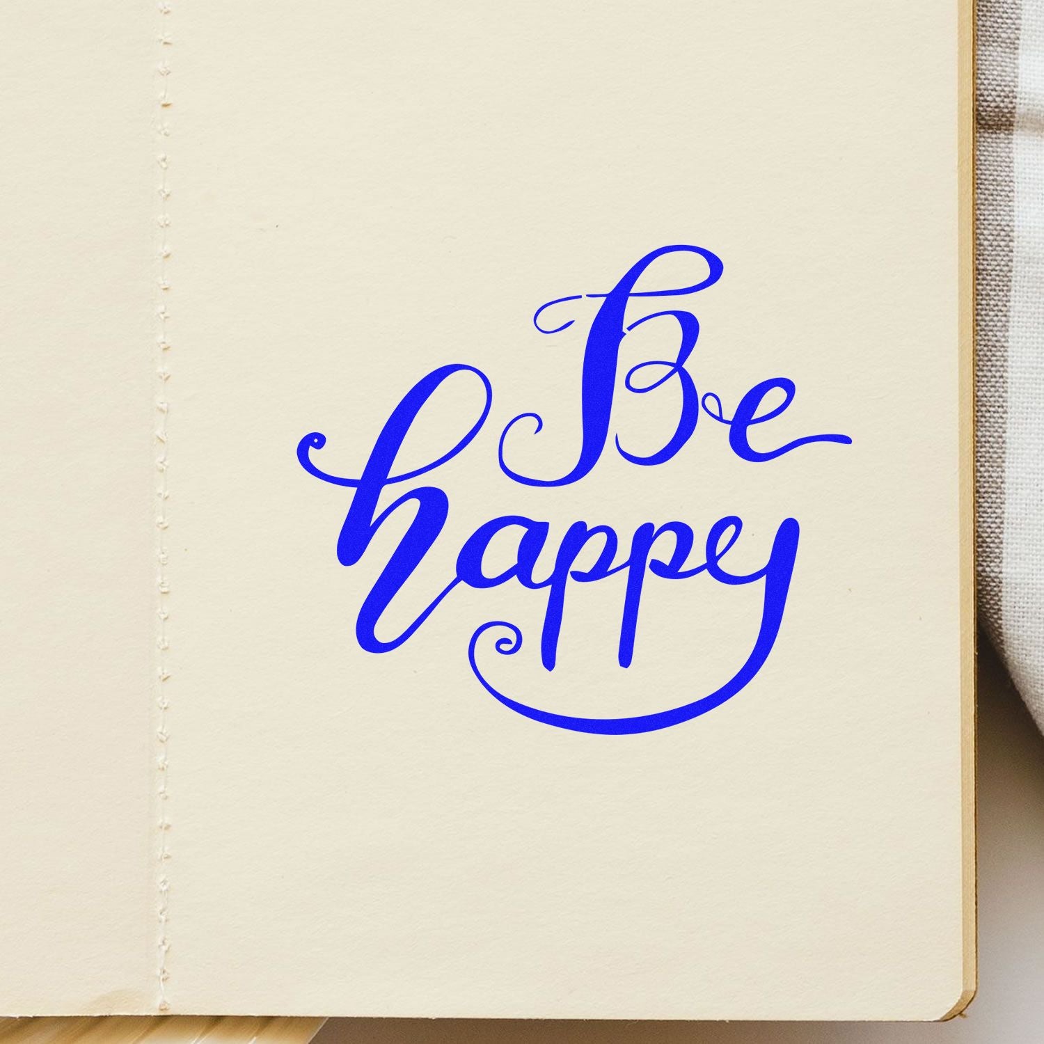 Blue Be happy calligraphy stamp seal on cream paper, with decorative swirls and bold blue script.