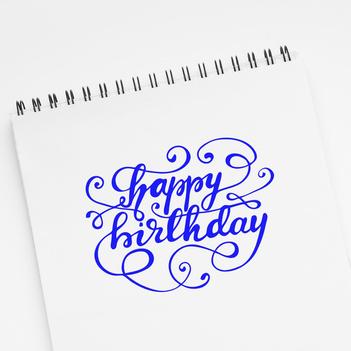 Blue ornate birthday stamp and seal design on a white spiral notebook page