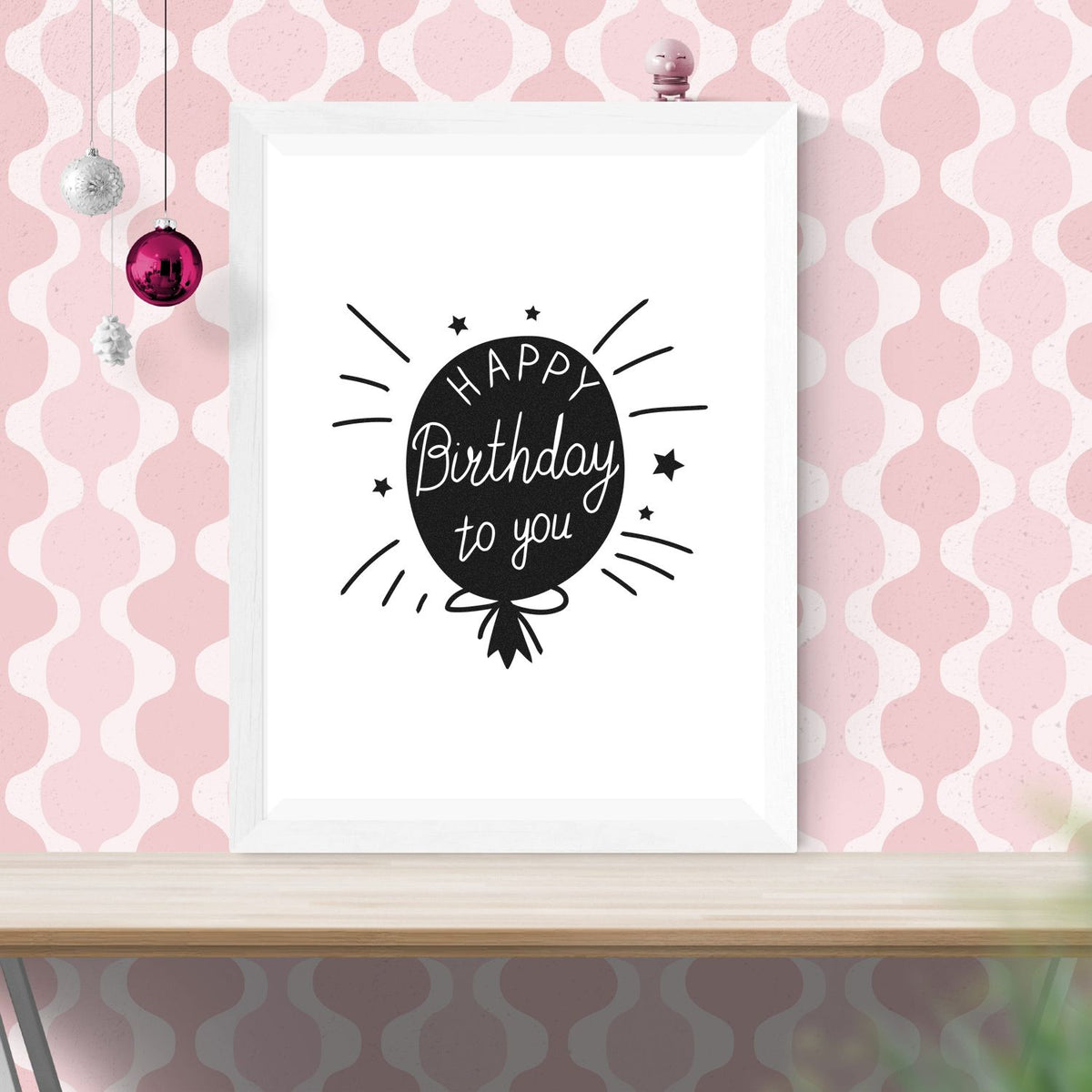Black Happy Birthday to you balloon stamp and seal design on a white frame, with a pink patterned background and ornaments.
