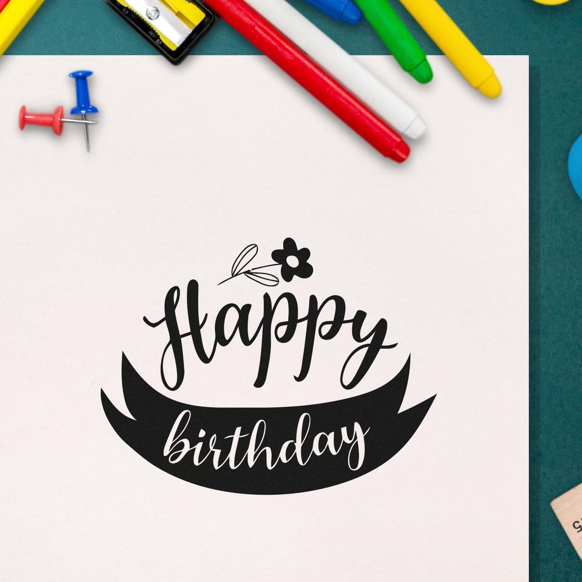 Happy Birthday Flower Ribbon Stamp - Premium Vintage Pro Wooden imprint stamped in black ink. Happy appears below a small flower and above birthday inside a curved dark ribbon.