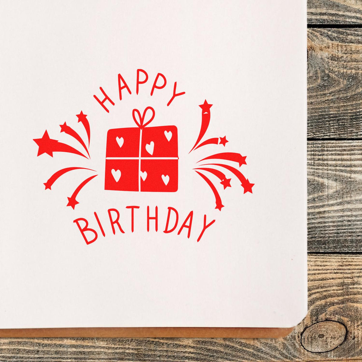 Red Happy Birthday stamp and seal design with gift, hearts, and starburst fireworks on white paper.