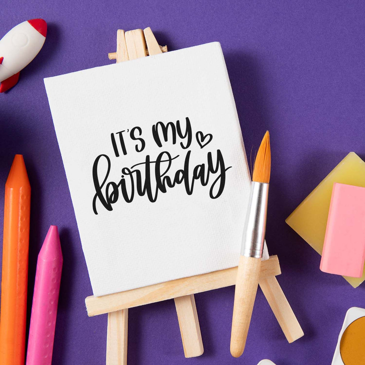 Birthday stamp and seal display with white canvas on easel, black script, purple background, colorful wax seals and tools