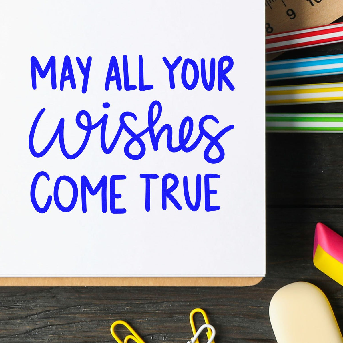 Blue lettering on white paper reads May all your wishes come true, beside colorful stamp and seal products.