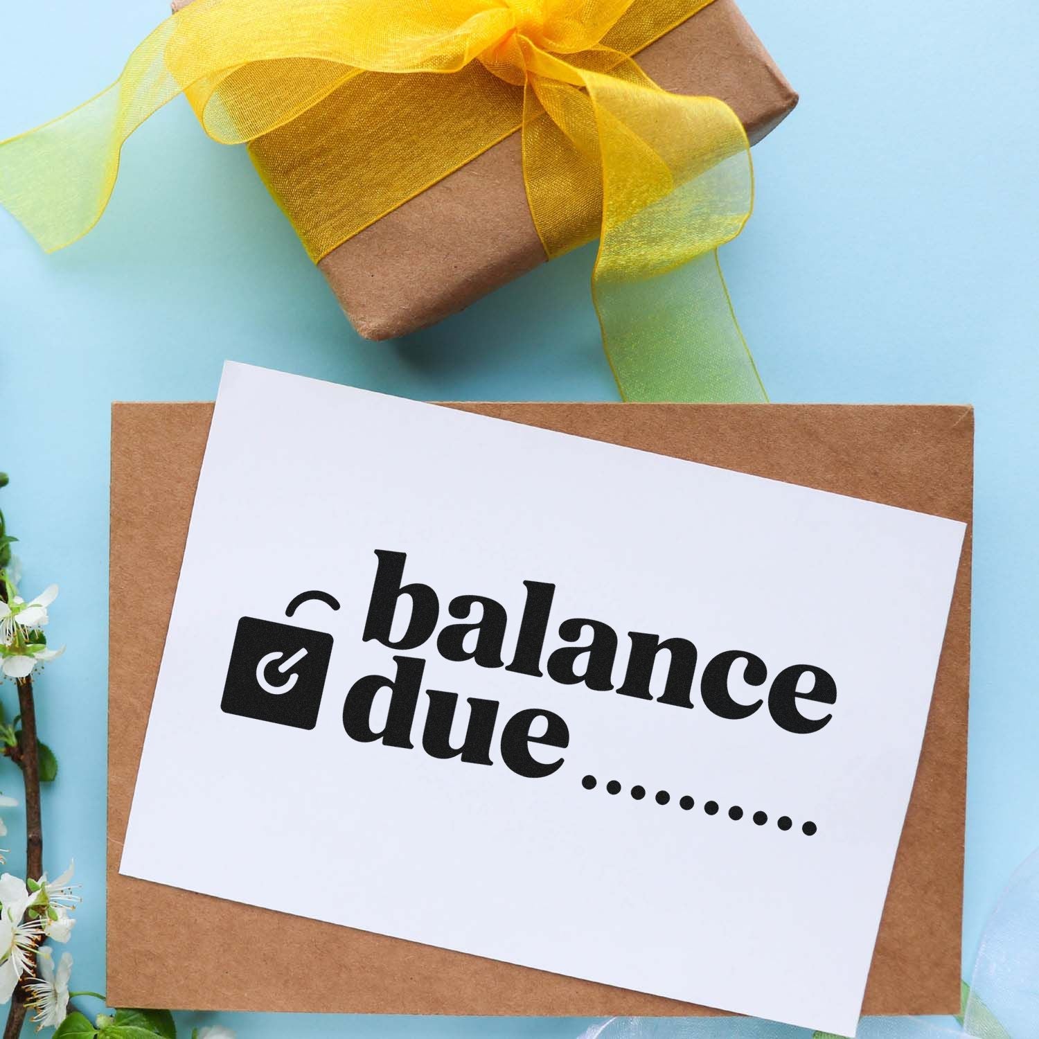 Brown kraft envelope with white balance due stamp and seal card, black text, tied with yellow ribbon on blue background.