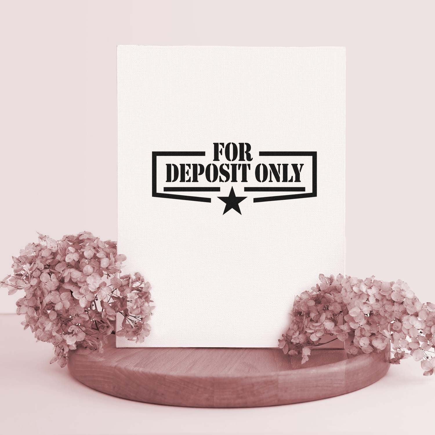 White stamp and seal package with black FOR DEPOSIT ONLY design, displayed on a wood base with soft pink flowers.