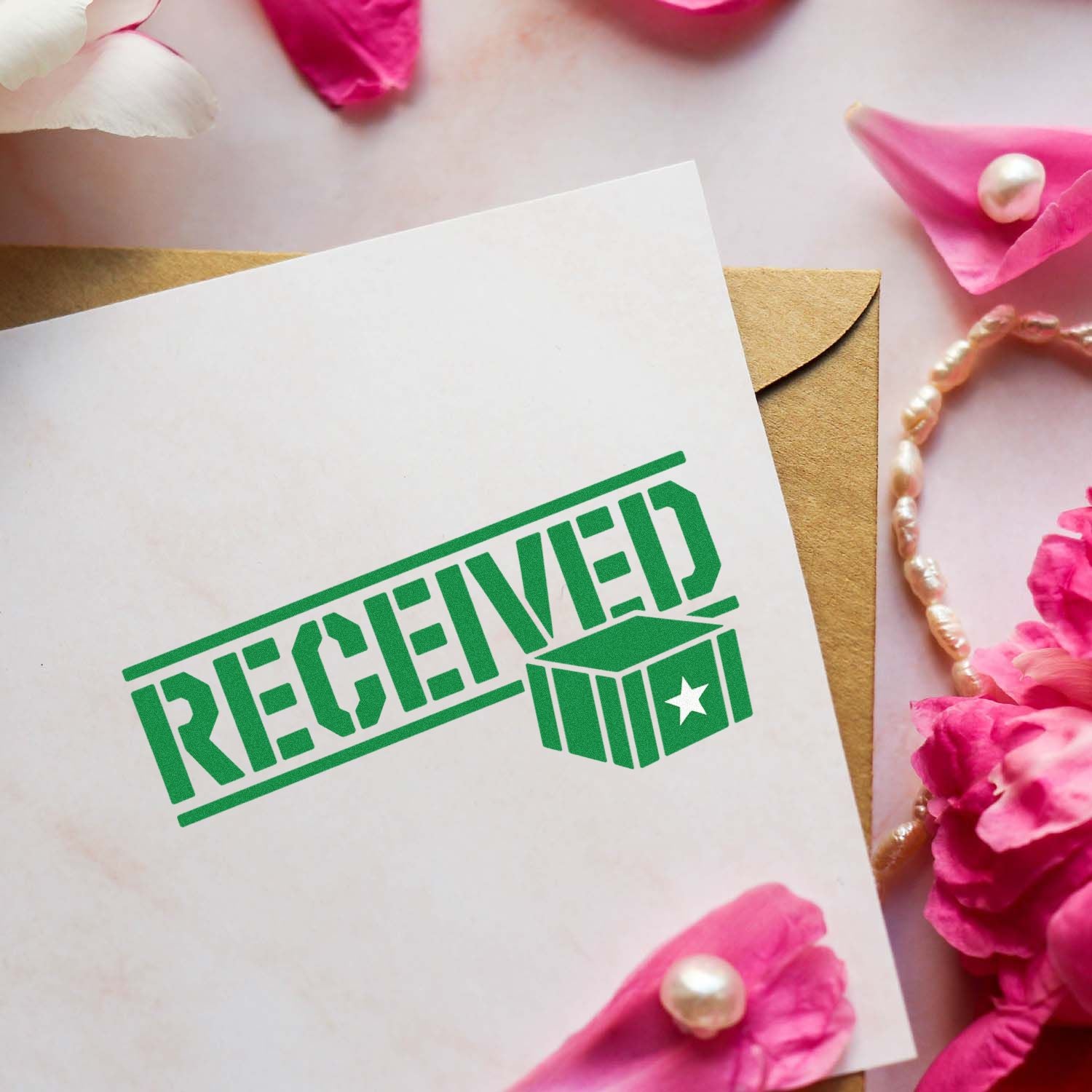 Green RECEIVED stamp seal on white card over kraft envelope, with pink petals and pearl accents.