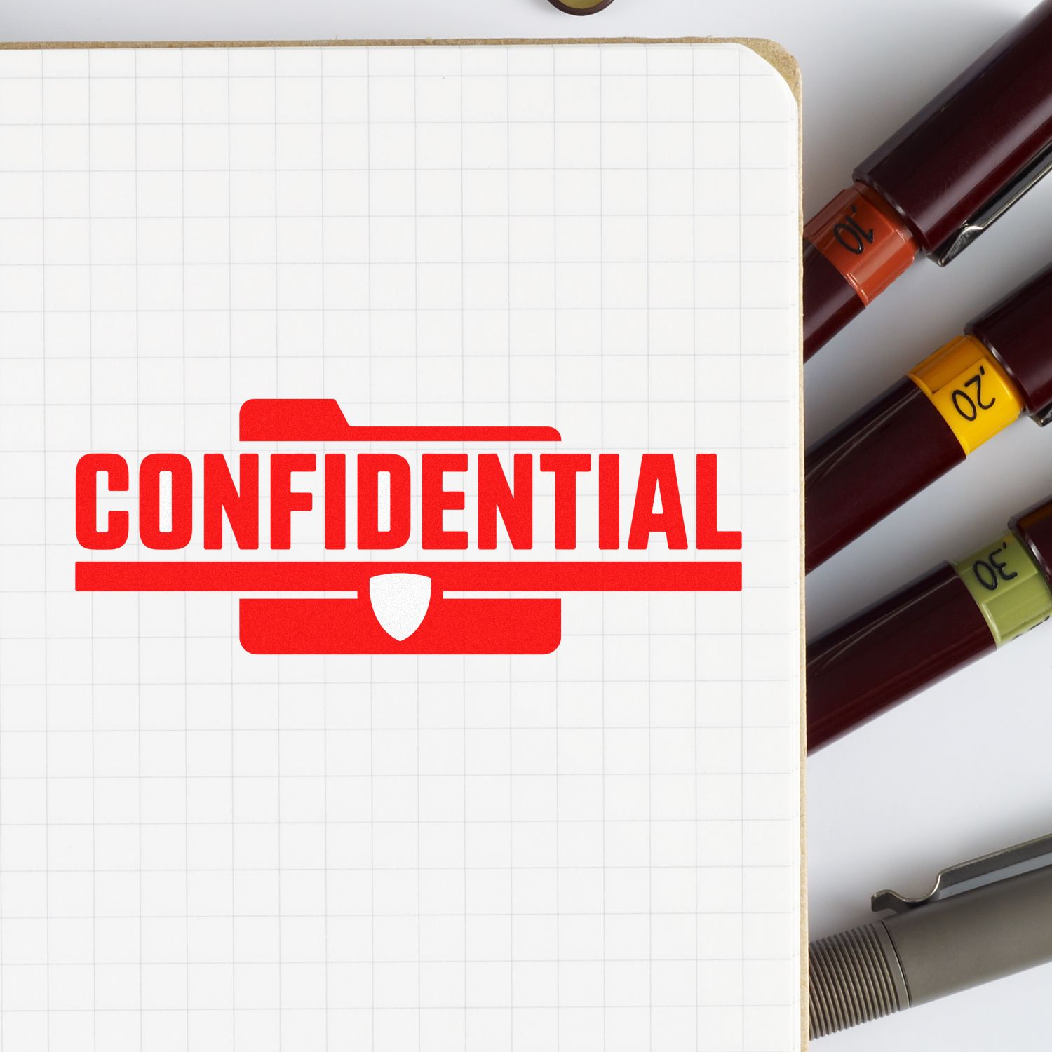 Red confidential stamp on grid paper beside stamp and seal markers with orange, yellow, and green bands.
