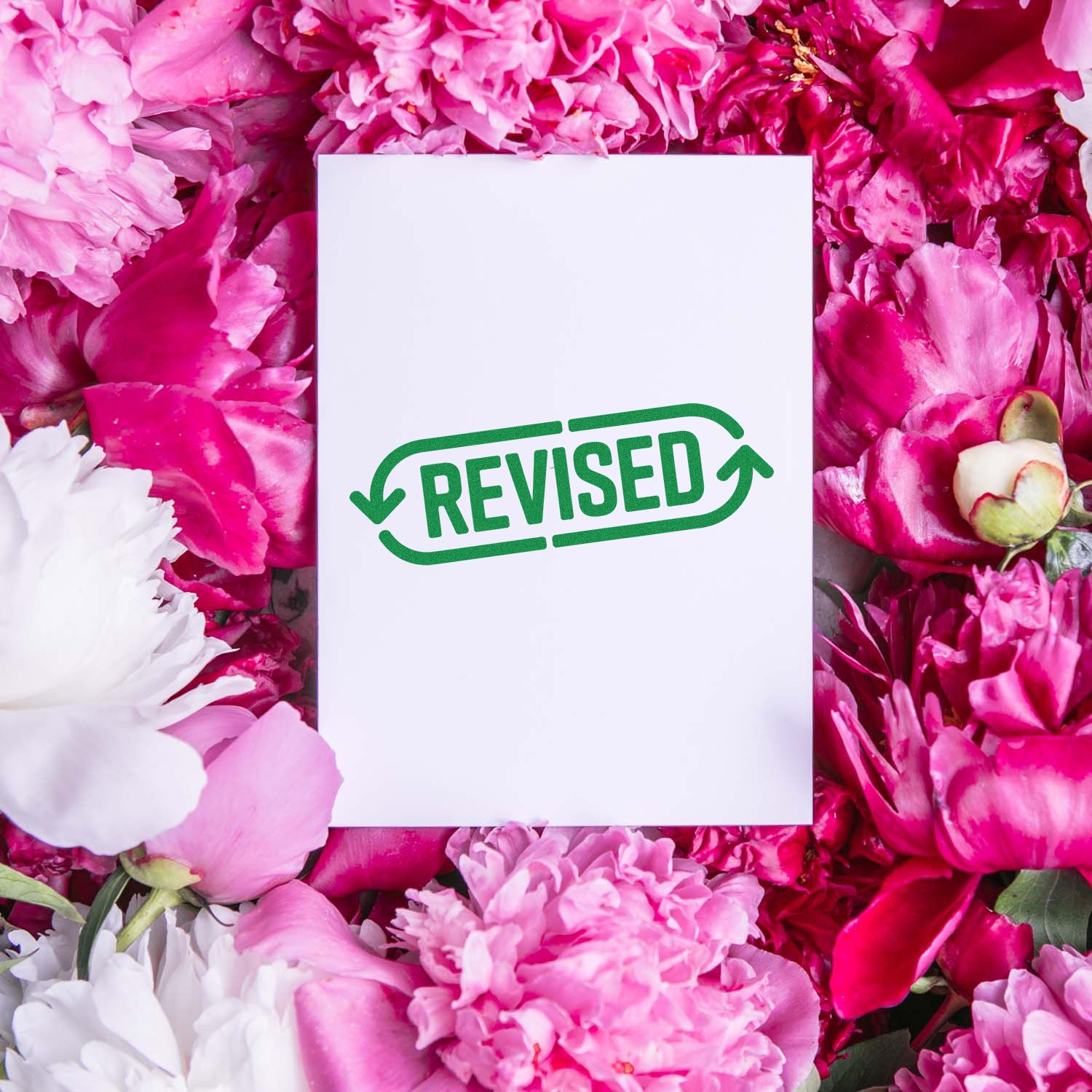 Green REVISED stamp on a white card, surrounded by pink and white flowers.