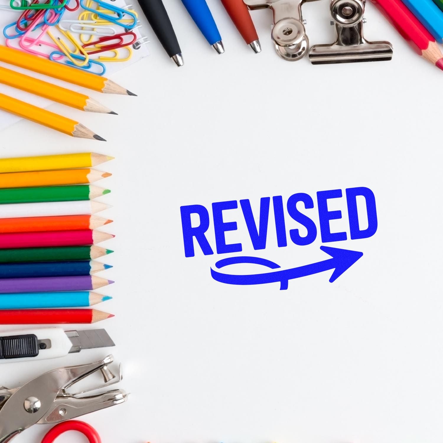 Blue REVISED stamp and seal supplies surrounded by colorful pencils, paper clips, binder clips, and tools.