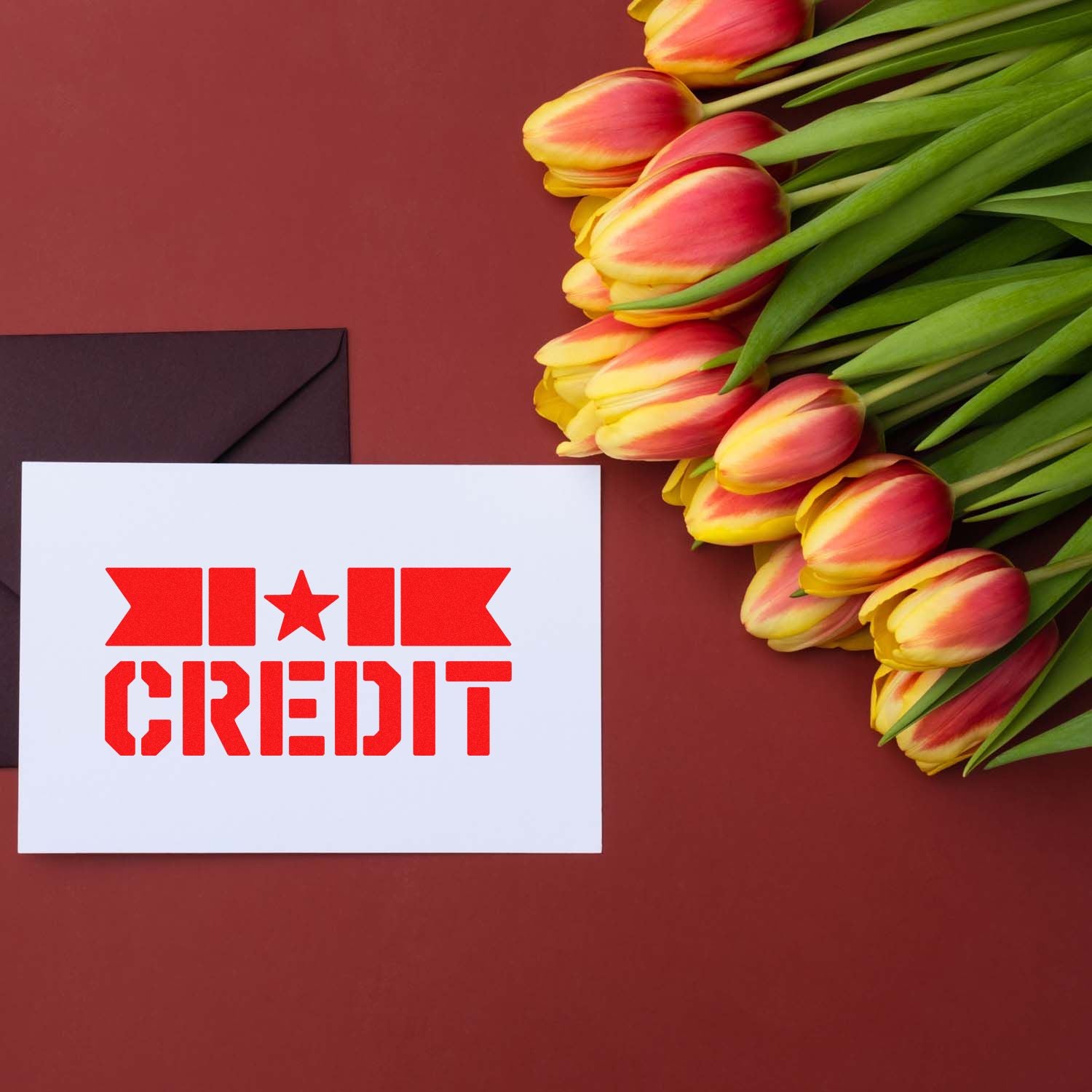 Red CREDIT rubber stamp on white card, with black envelope and pink-yellow tulips on a burgundy background.