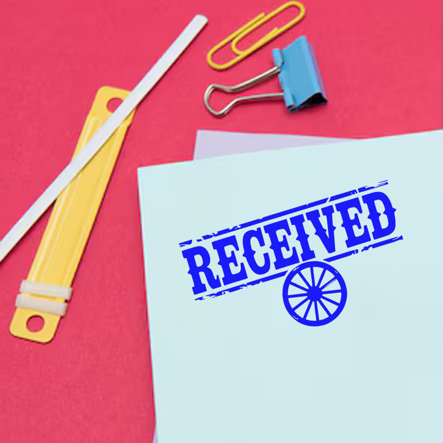 Blue RECEIVED stamp and seal mark on paper, with yellow clip and paperclip on a bright pink background.
