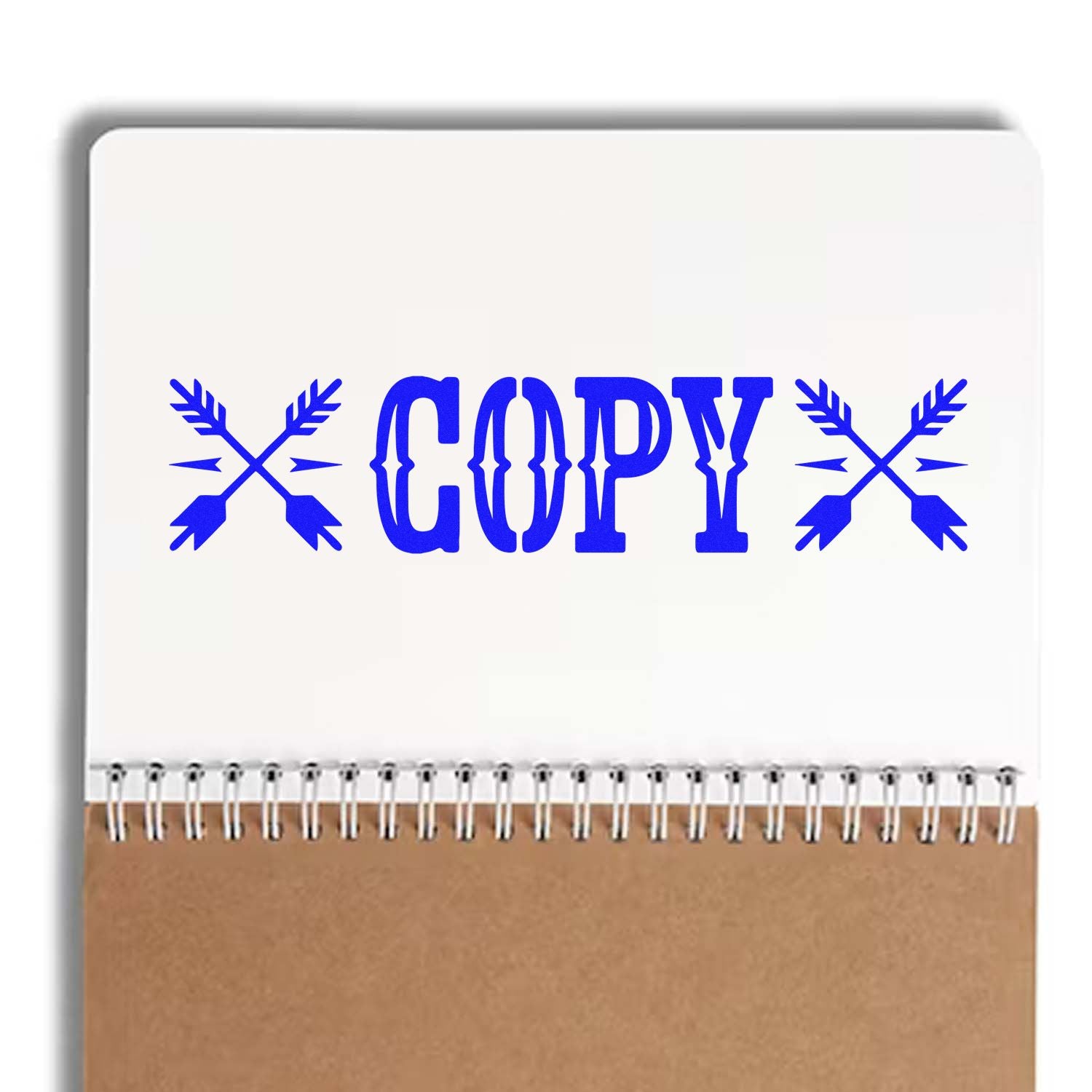 Blue COPY stamp and seal design on a white spiral notebook with brown cover and arrow motifs.