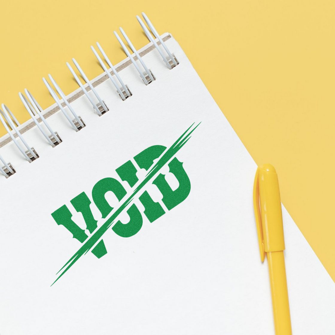 White spiral notebook with green PAID stamp seal and yellow pen on a yellow background