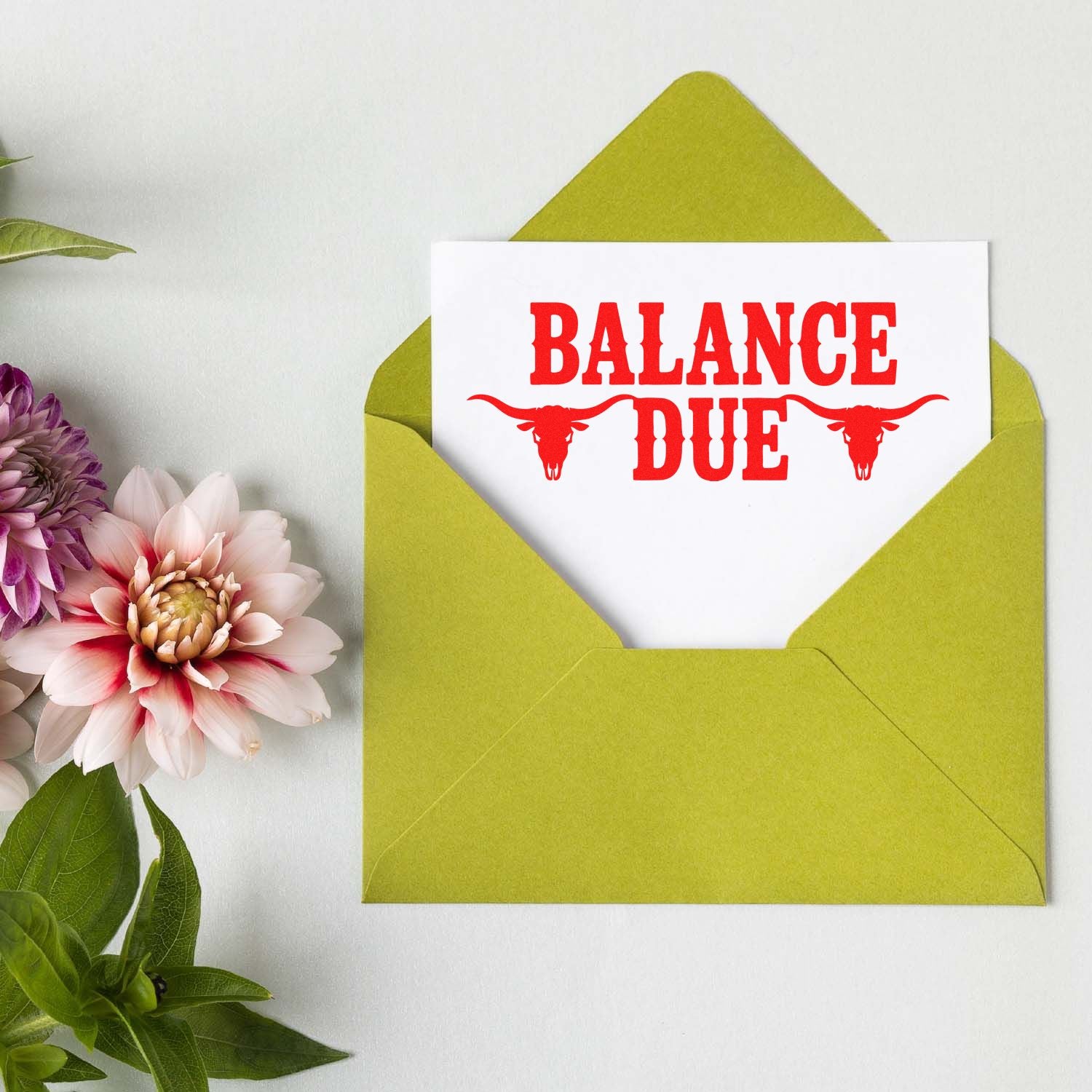 Red BALANCE DUE stamp and seal with longhorn skulls on white card in a lime green envelope.