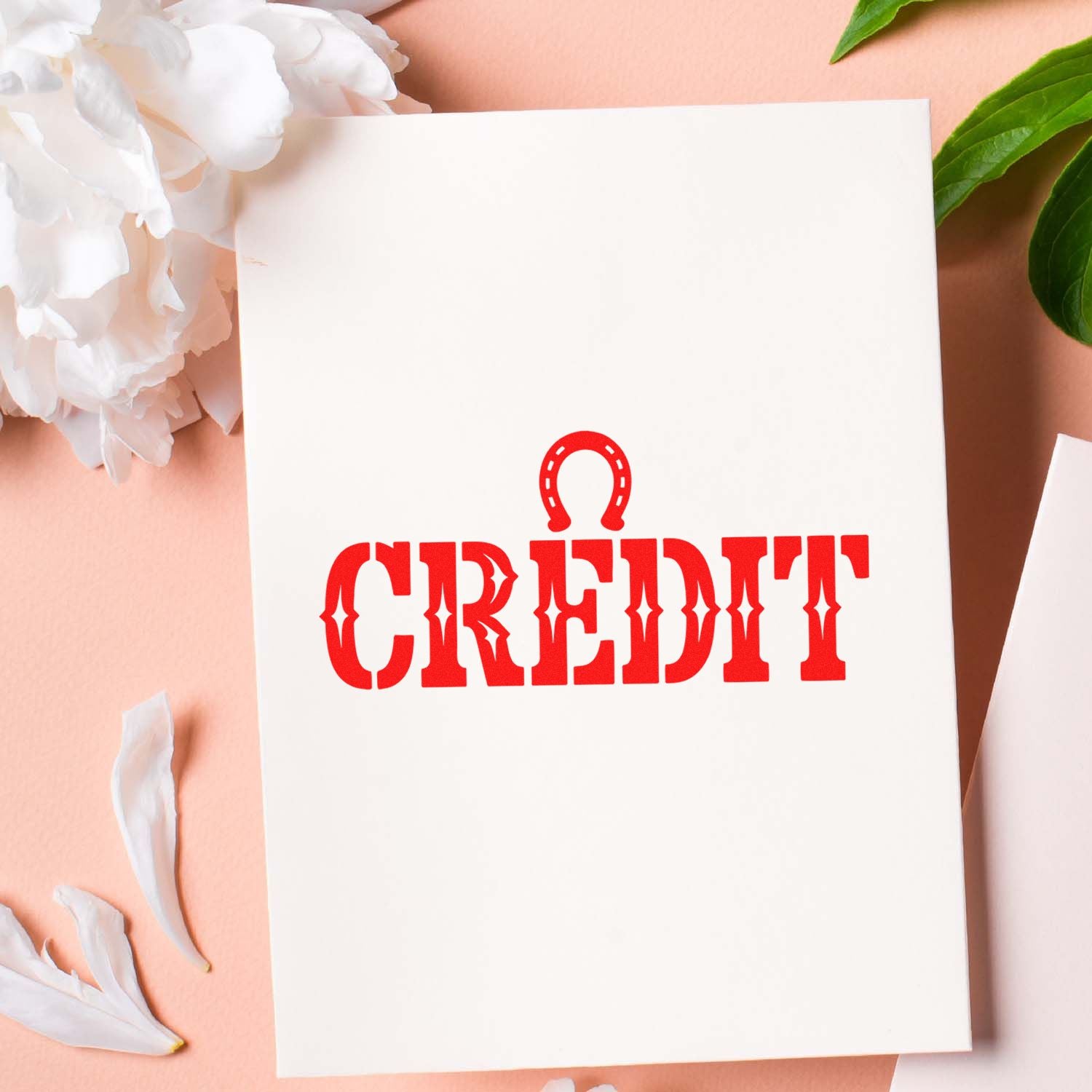White card with red CREDIT stamp and horseshoe seal icon on a soft pink background with white petals and green leaves.