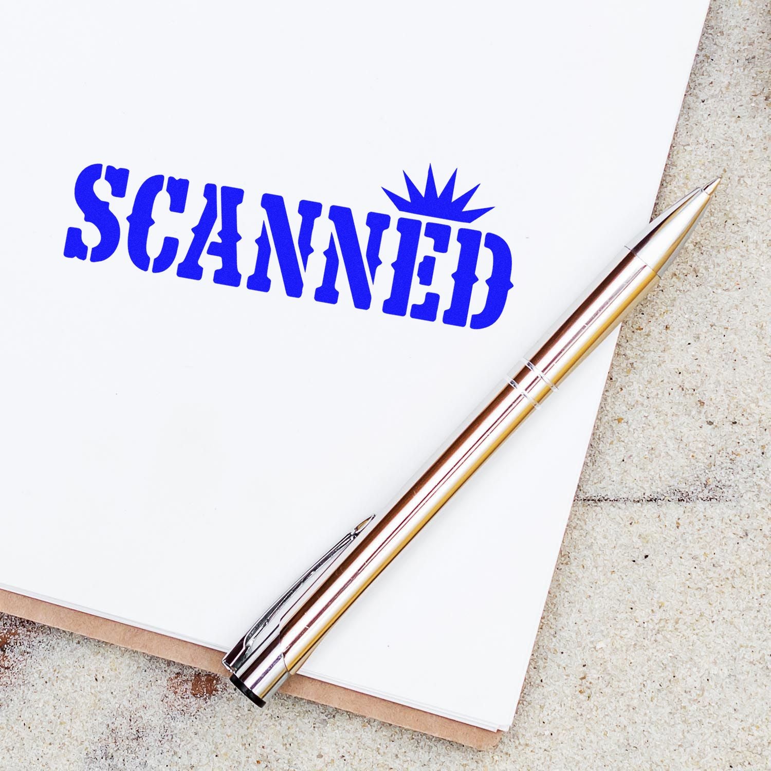 Blue SCANNED rubber stamp on white paper beside a metallic pen, with a stamp-and-seal look.