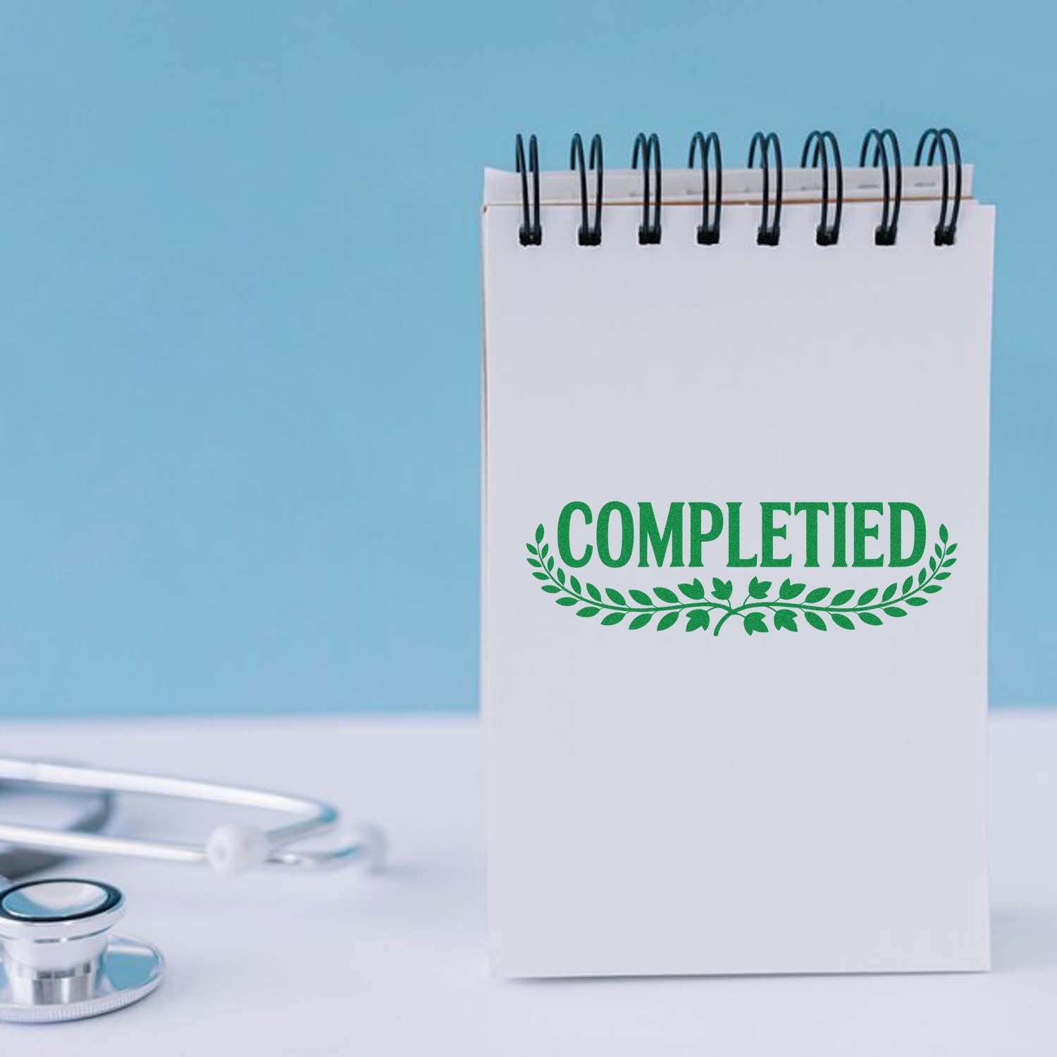 Spiral notepad with green COMPLETED seal stamp, on light blue background, beside a stethoscope.