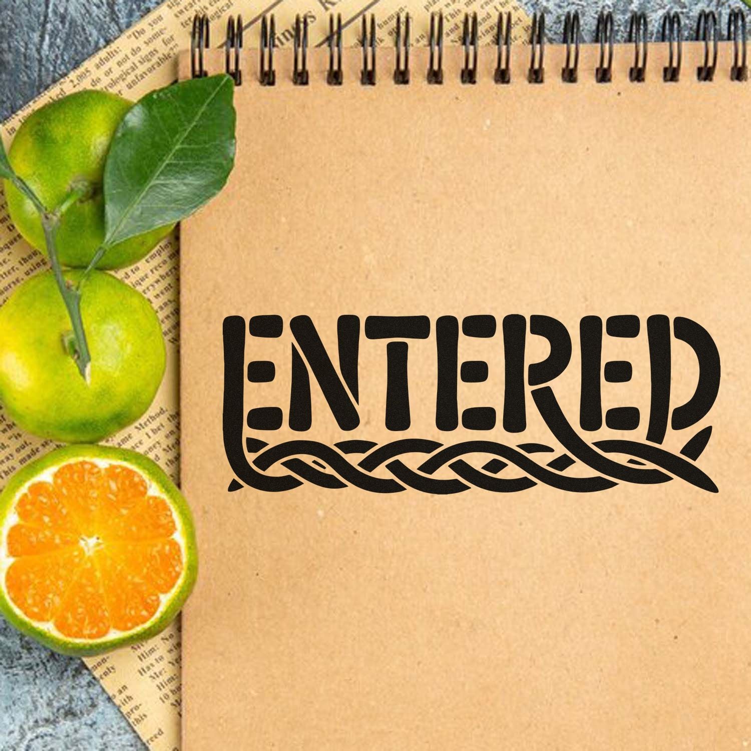 Black ENTERED stamp and seal on kraft notebook, framed by green citrus fruit and an orange slice.