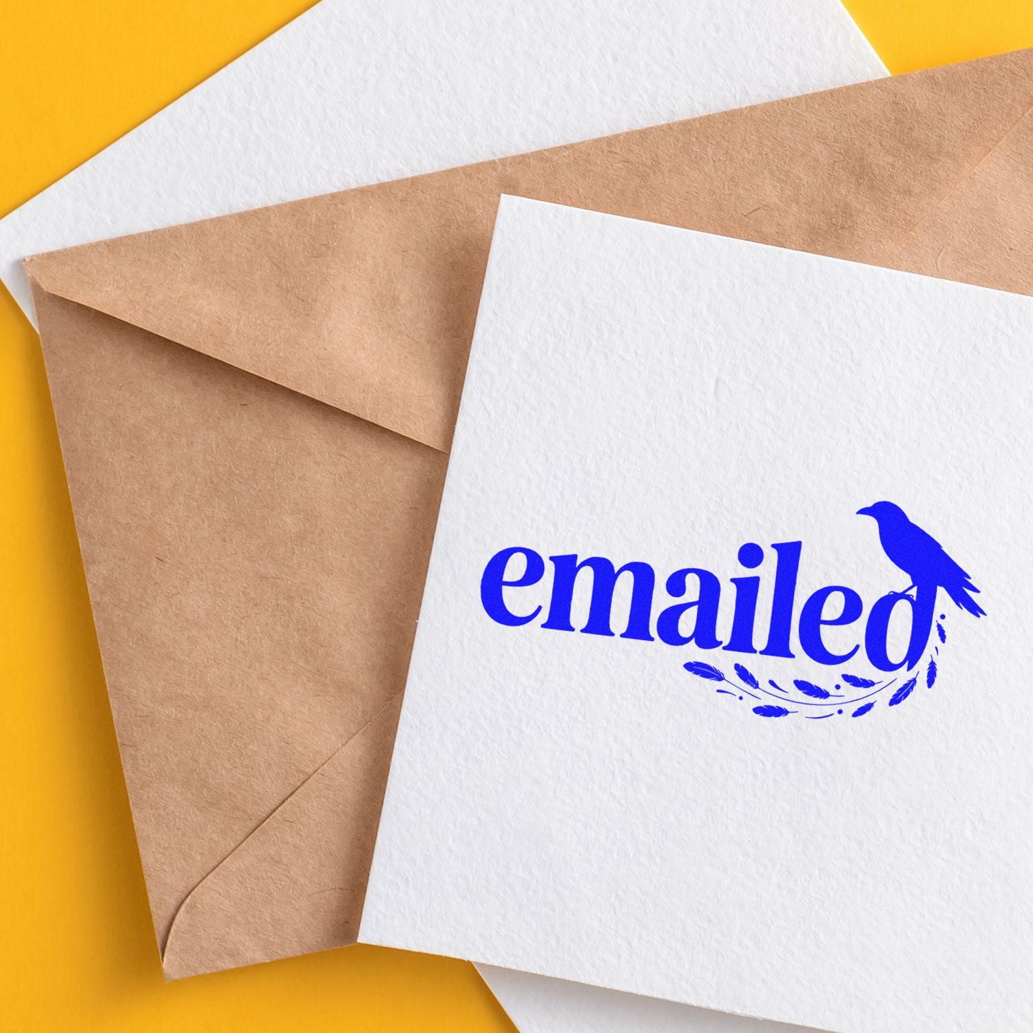 Blue "emailed" stamp and bird seal on white card, with kraft envelope on a bright yellow background.