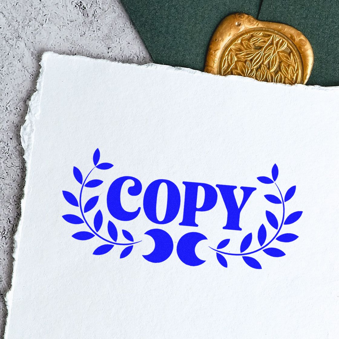 Blue COPY stamp with laurel leaves on white textured paper, beside a gold wax seal on dark green and gray background.