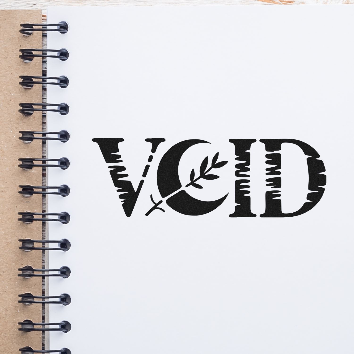 Black VCD stamp and seal logo with leaf in the C on a white spiral notebook page.