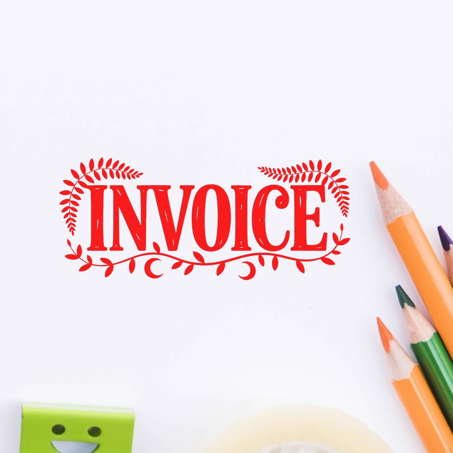 Red decorative INVOICE stamp seal on white paper with leafy border and colored pencils nearby.