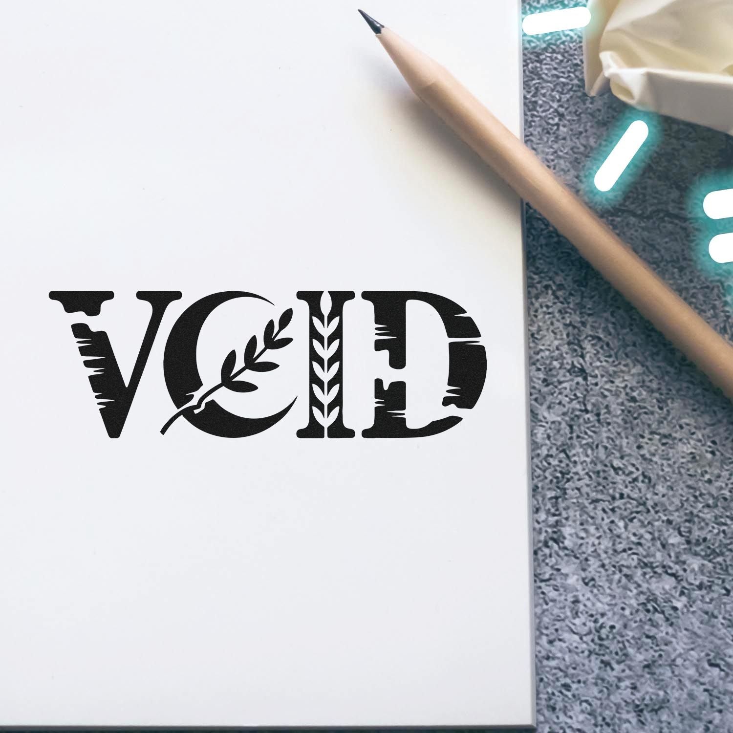 Black VOID security seal stamp on white paper beside a beige pencil on a gray textured surface.