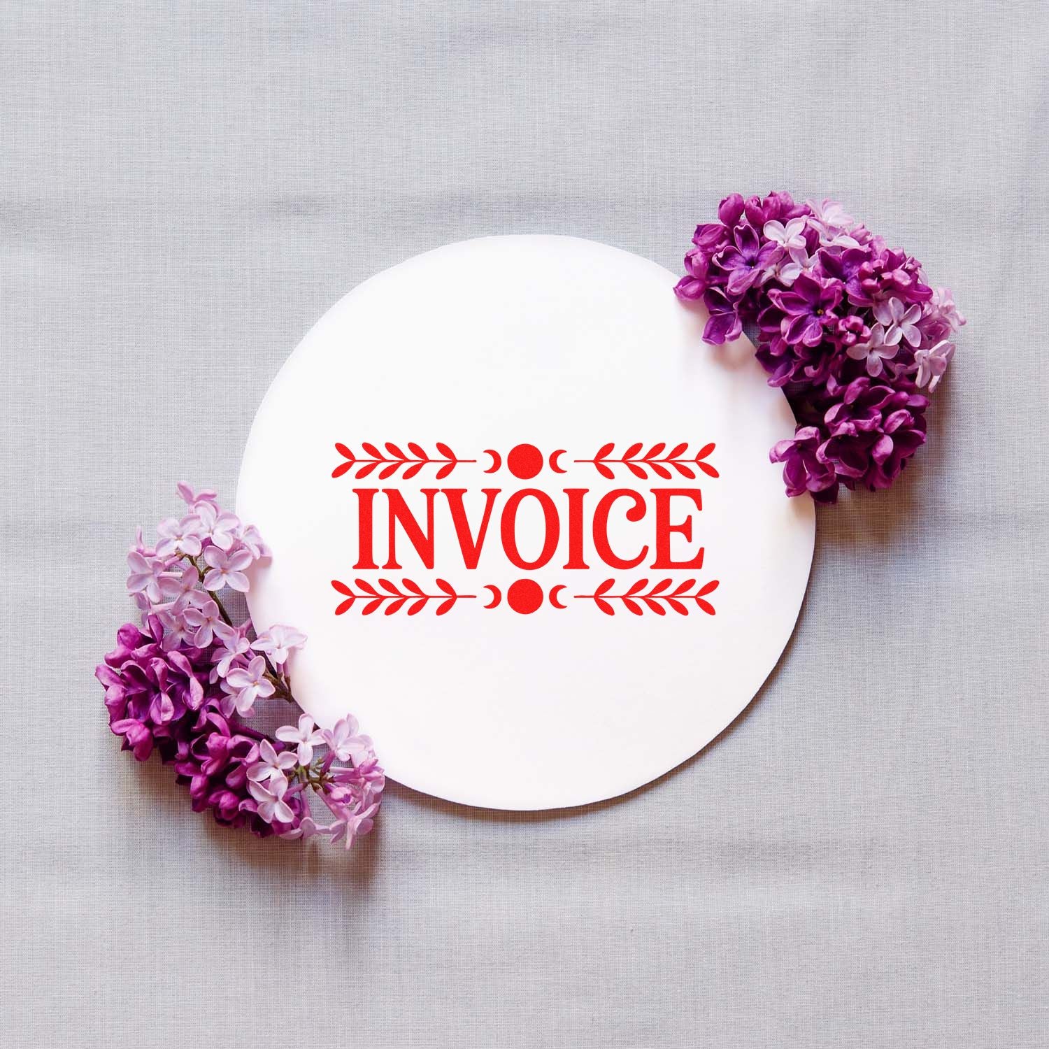 White circular invoice stamp seal with red lettering, framed by purple lilac flowers on beige fabric.