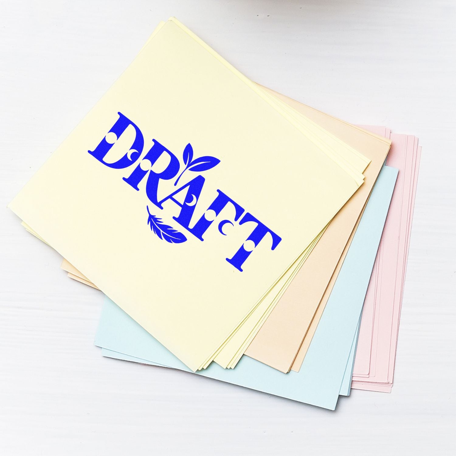 Pastel paper sheets with bold blue DRAFT stamp, showcasing stamp and seal product samples in cream, pink, blue, and beige.