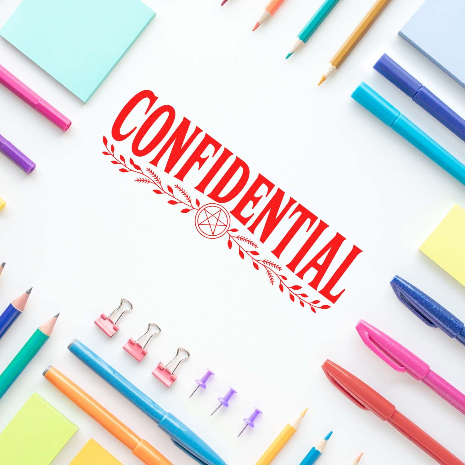 Red CONFIDENTIAL stamp seal on white paper, surrounded by colorful pens, pencils, binder clips and sticky notes.