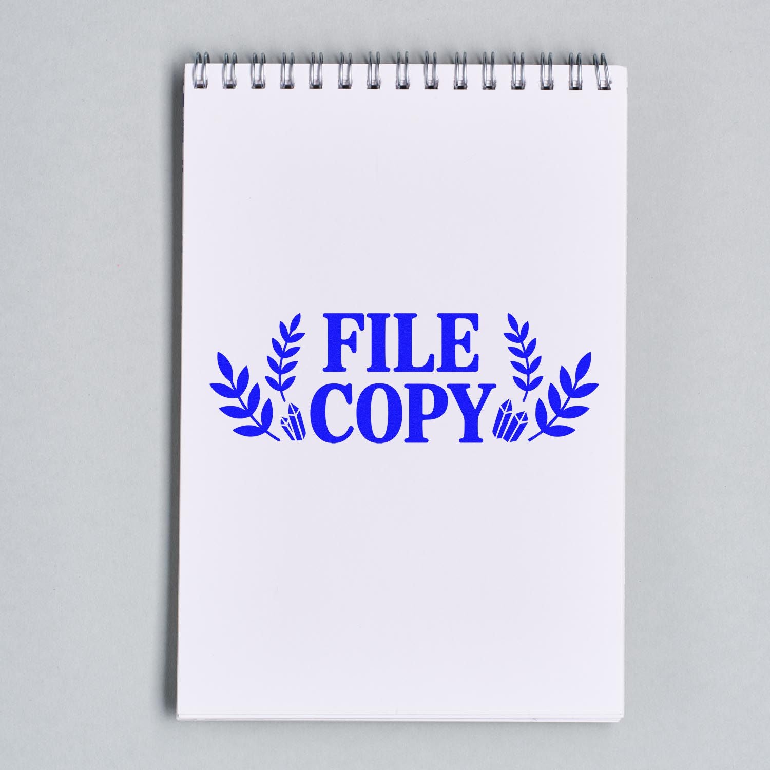 Blue FILE COPY stamp seal with laurel leaves on a white spiral notebook.