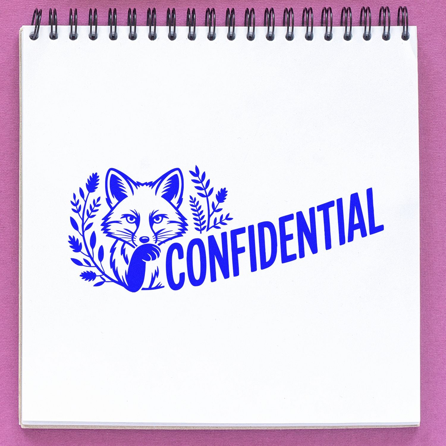 Blue confidential fox stamp seal on white spiral notebook, pink background