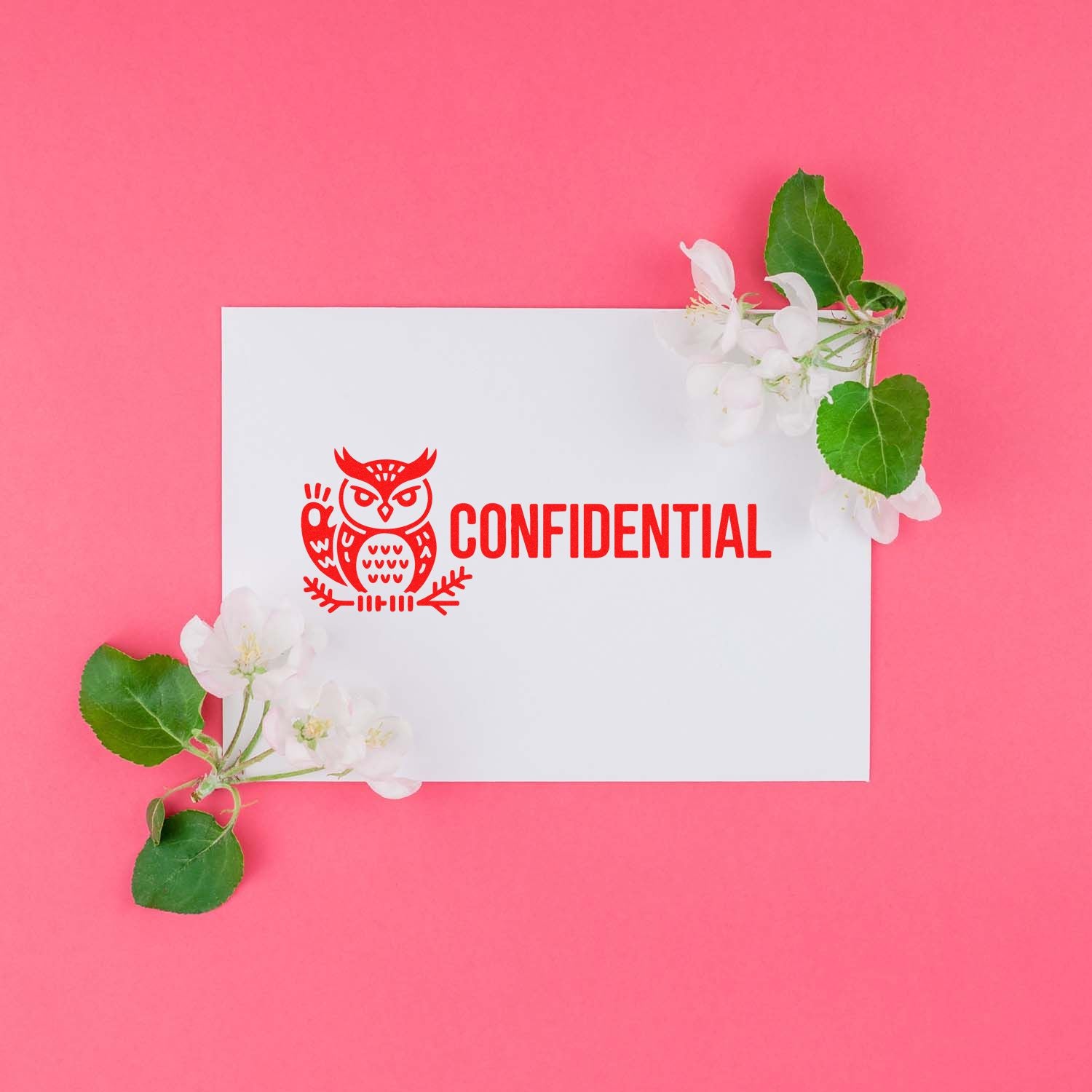 White card with red confidential owl stamp seal on pink background, framed by white blossoms and green leaves.