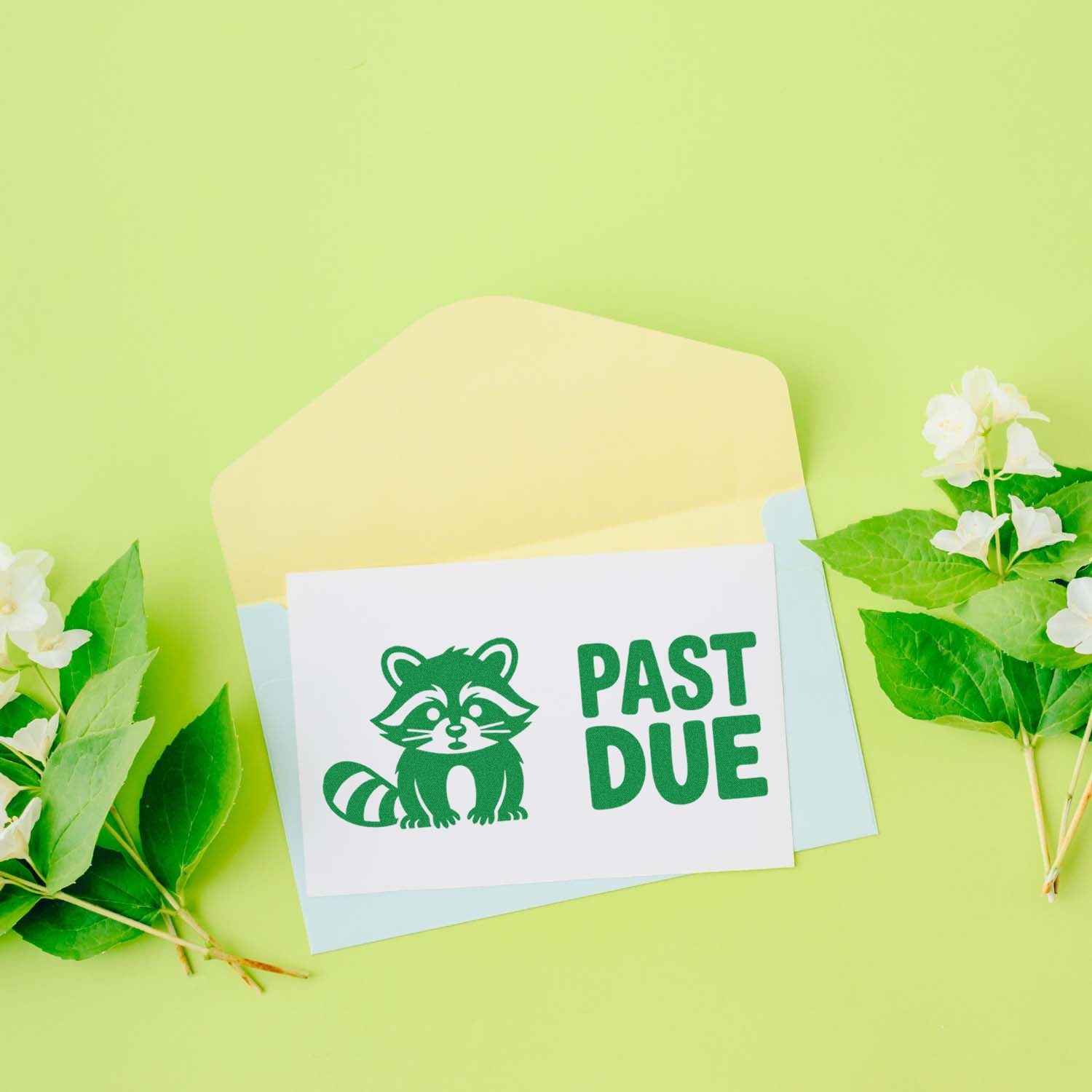 Green raccoon PAST DUE stamp and seal on white card with pastel envelopes, green leaves, and white flowers.