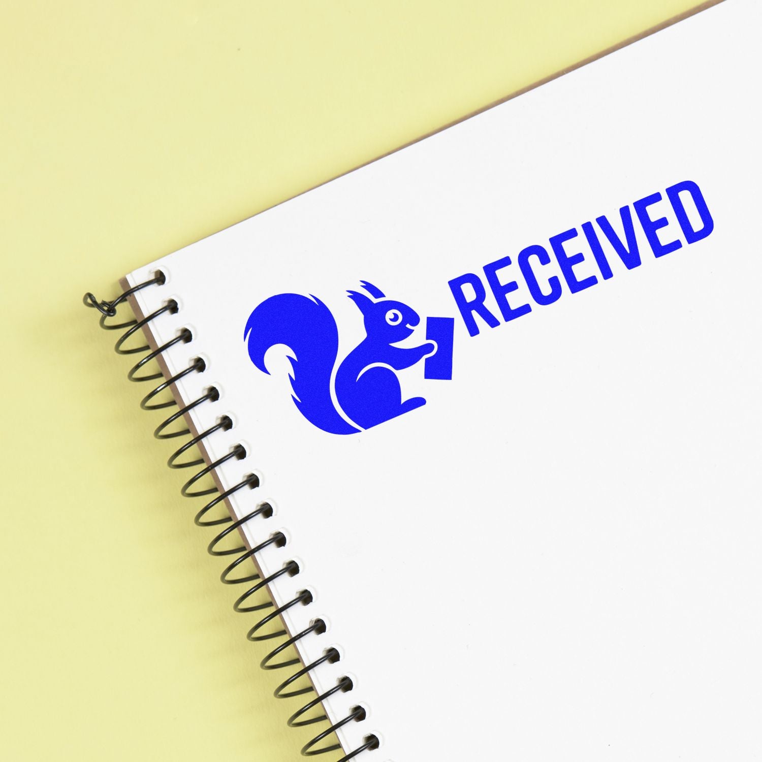 White spiral notebook with a blue Received stamp seal and squirrel logo on a pale yellow background.