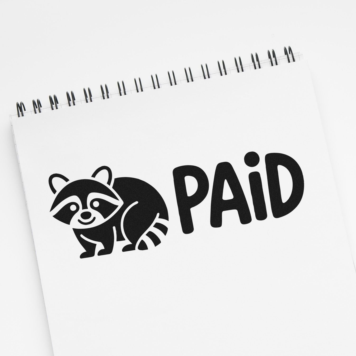 Black PAID stamp seal with raccoon icon on a white spiral notepad