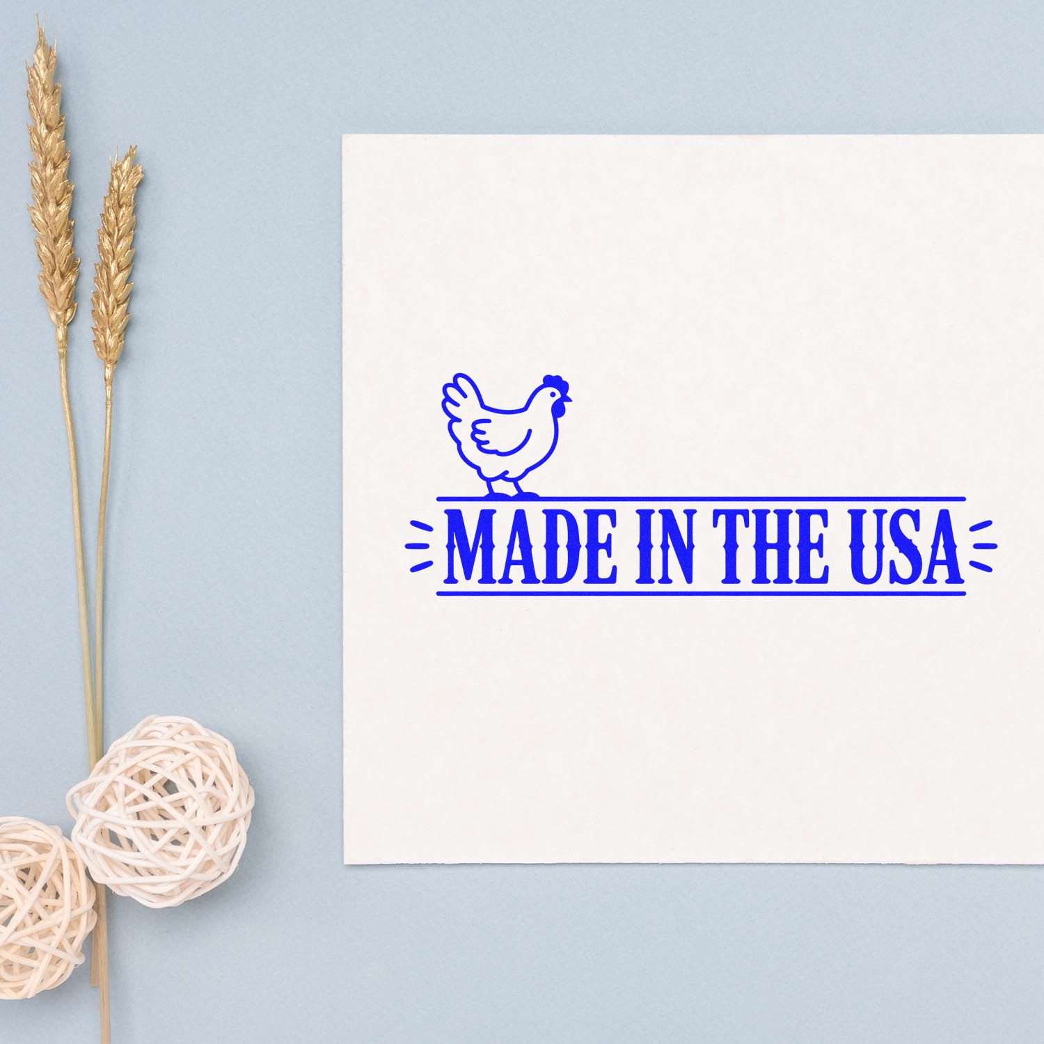 Blue Made in the USA chicken stamp seal on a white card, with pale blue background and wheat stalk decor.