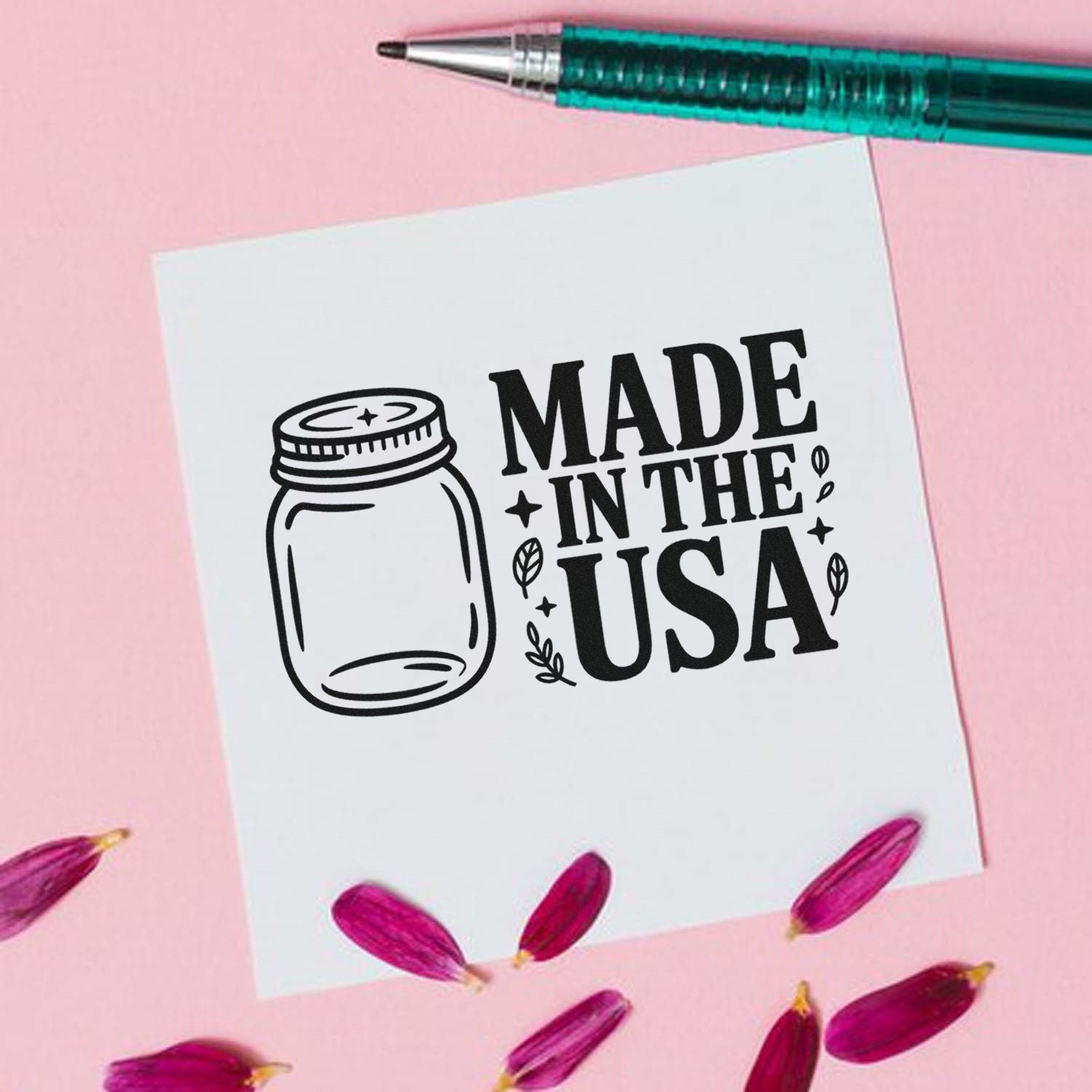 Black Made in the USA mason jar stamp design on white paper, with teal pen, pink background, and magenta petals.